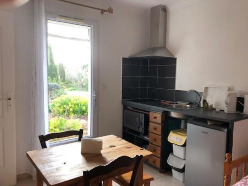 une cuisine avec une table en bois, une table et une fenêtre dans l'établissement LA LAVANDIERE, à Peyriac-de-Mer