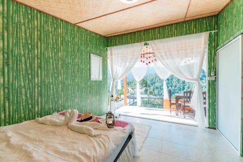 a bedroom with green walls and a bed with a window at สวนส้มลุงเก๊าโฮมสเตย์แม่แตง in Ban Mae Na