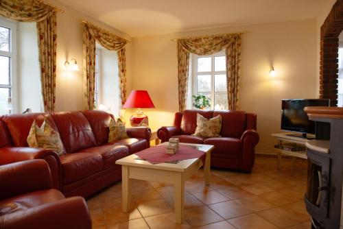 a living room with leather couches and a tv at Lütje Huus in Norden