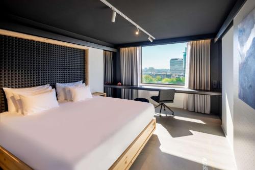 a bedroom with a large bed and a large window at nhow Brussels Bloom in Brussels