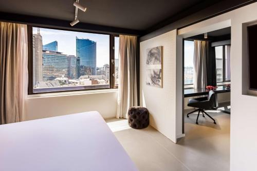 a bedroom with a bed and a desk and a window at nhow Brussels Bloom in Brussels