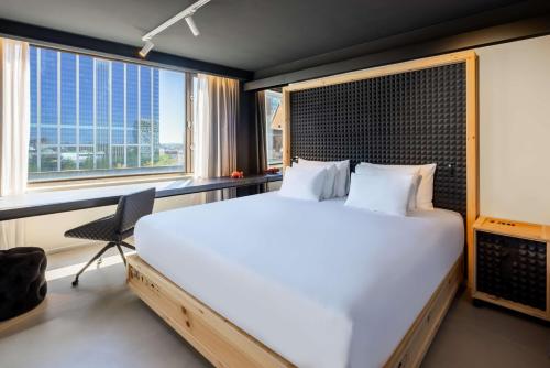 a bedroom with a large bed and two windows at nhow Brussels Bloom in Brussels