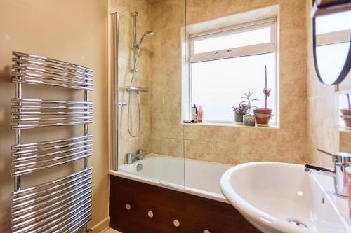 a bathroom with a tub and a sink and a window at Cosy home in Chapel Allerton Area - Peaceful Street, Free Parking in Leeds