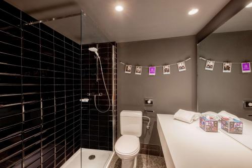 a bathroom with a toilet and a shower with black tiles at nhow Brussels Bloom in Brussels