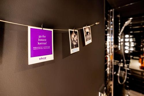 a group of pictures hanging from a clothes line in a bathroom at nhow Brussels Bloom in Brussels