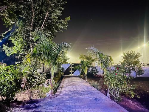 a walkway with palm trees and a building at night at The Luxe Villa by Vaaranya Group in Varanasi