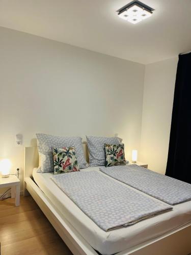 a white bedroom with a large bed with pillows at B2 Apartman in Balatonszemes