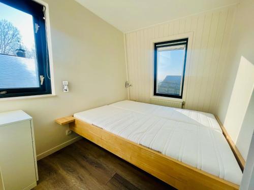 ein kleines Schlafzimmer mit einem Bett und zwei Fenstern in der Unterkunft Lamsoor 9A* in Nieuwvliet