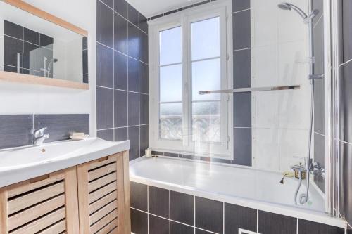 a bathroom with a tub and a sink and a window at Résidence royale T3 in Dreux