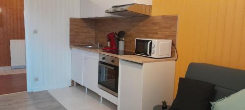 une petite cuisine avec un micro-ondes et une cuisinière dans l'établissement Au Bon oranger, Appartement en coeur de ville hyper centre, à Cholet