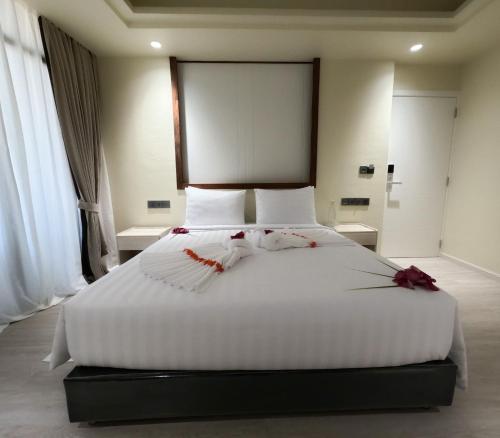 a bedroom with a large white bed with red flowers on it at Aquaraa in Maduvvari