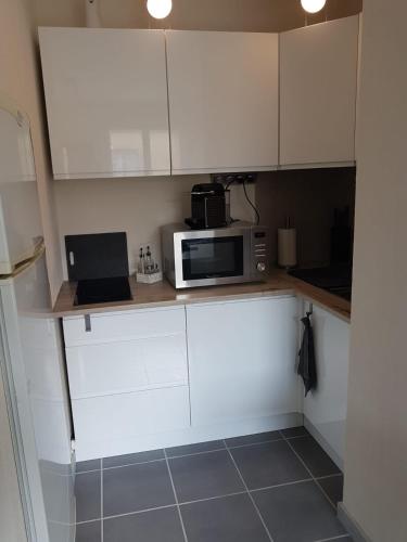 une cuisine avec des placards blancs et un four micro-ondes sur un comptoir dans l'établissement Studio les pieds dans l'eau, au Grau-du-Roi