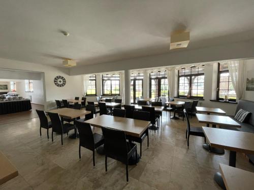 a dining room with tables and chairs and windows at Stary Tartak in Iława