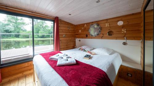 une chambre avec un lit avec une couverture rouge dans l'établissement Village Toue du Domaine des Demoiselles, à Chassenard