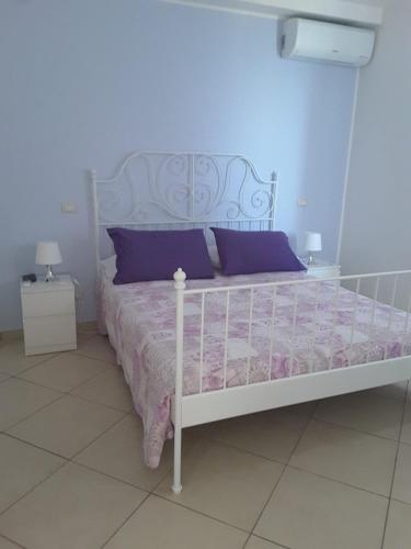 ein Schlafzimmer mit einem weißen Bett und lila Kissen in der Unterkunft Iriss in Taormina