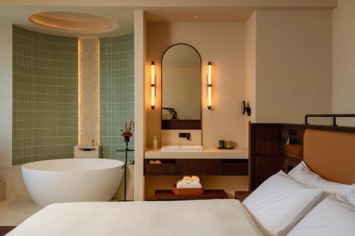a bathroom with a tub and a sink and a bed at Papman Hotel Kunming Xishan Wanda Branch in Kunming