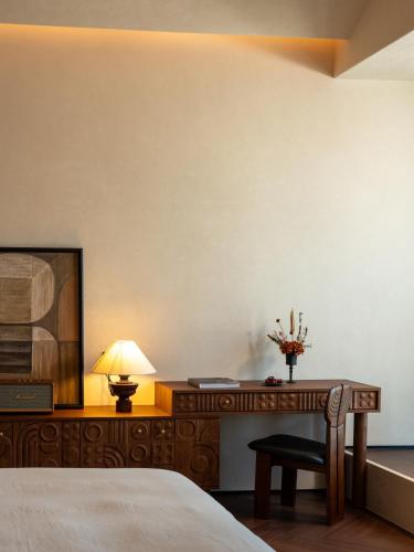 a bedroom with a bed and a desk with a lamp at Papman Hotel Kunming Xishan Wanda Branch in Kunming
