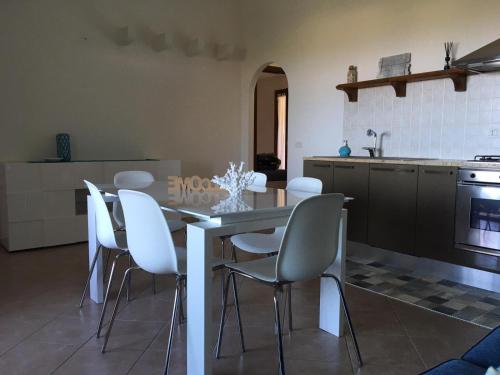 a kitchen with a dining table and white chairs at Bellavista San Teodoro appartamento vista mare in Lu Lioni