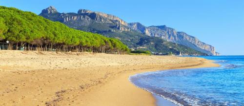 a sandy beach with a mountain in the background at Tiny House Bellavista in Bari Sardo