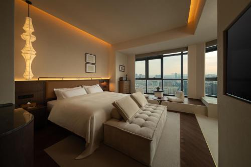a bedroom with a bed and a couch and windows at Papman Hotel Kunming Xishan Wanda Branch in Kunming