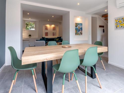 une salle à manger avec une table en bois et des chaises vertes dans l'établissement Jolie maison familiale - 2km port et plages - CX, à Antibes