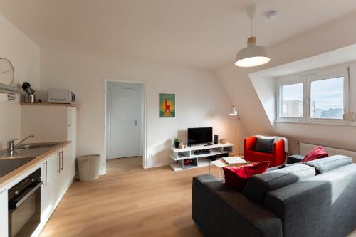 a living room with a gray couch and a kitchen at Le 16 - Parking city center in Colmar