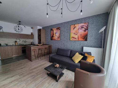 een woonkamer met een bank en een keuken bij Q Apart GRAND - 3 pokojowe klimatyzowane apartamenty przy Manufakturze z garażem Gratis, FV in Łódź