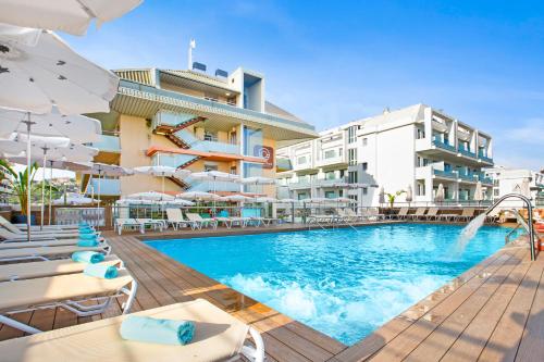 a pool at a hotel with chairs and umbrellas at Aparthotel Odissea Park in Santa Susanna