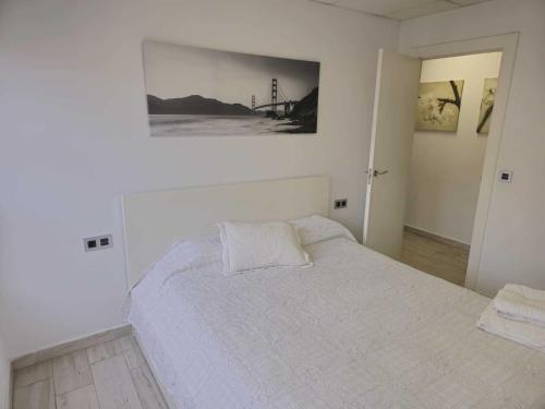 a bedroom with a white bed with a picture on the wall at Apartamentos Arena y Cairo in Murcia