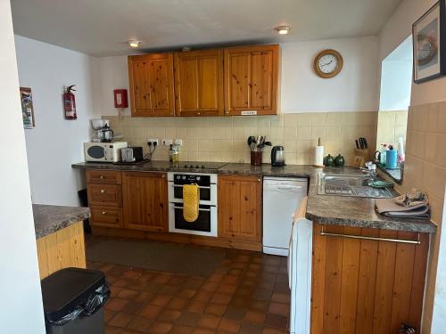 a kitchen with wooden cabinets and a stove top oven at Cranstakie Cottage in Durness