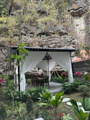 a pavilion with a table and chairs in a garden at Tam Coc Wonderland Lodge in Ninh Binh