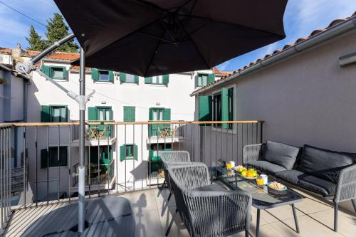 a balcony with a table and chairs and an umbrella at Apartments Korta in Split