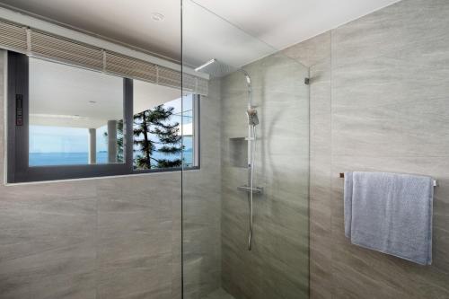 Un baño con ducha con puerta de cristal. en Penthouse 2BR Seaview Top Floor, en Ban Thong Phlu
