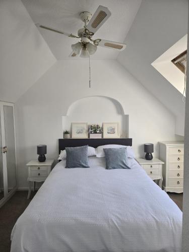 a bedroom with a white bed with a ceiling fan at Beautiful apartment with private pool near Tenby in Kilgetty