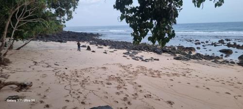 a couple of people walking on a beach at Puri Ma'u Beach & Bungalows in Boba