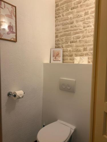 La salle de bains est pourvue de toilettes blanches et d'un mur en briques. dans l'établissement La Rose des Vins, à Pouzolles