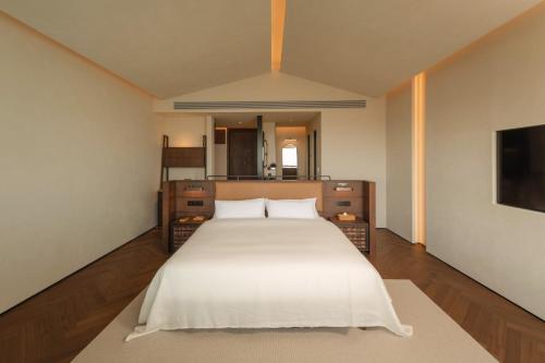 a bedroom with a large white bed and a mirror at Papman Hotel Kunming Xishan Wanda Branch in Kunming