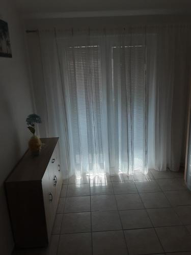 a room with white curtains and a table with a vase at Apartma Igor s parkiriščem in Medulin