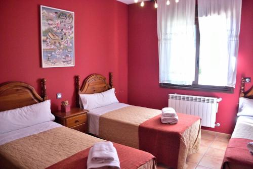 a room with two beds with red walls at Finca La Vega Bul in Estremera