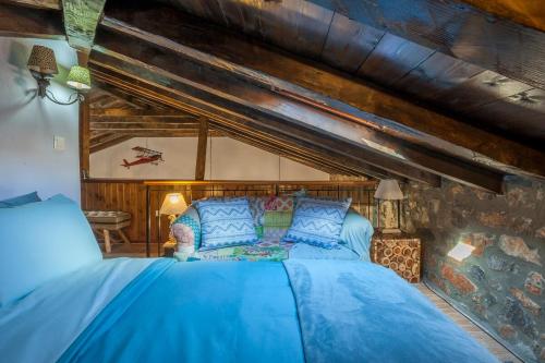 a bedroom with a blue bed in a stone wall at Dandy Villas Palios Agios Athanasios - Attic - Fireplace - Village Square in Palaios Agios Athanasios