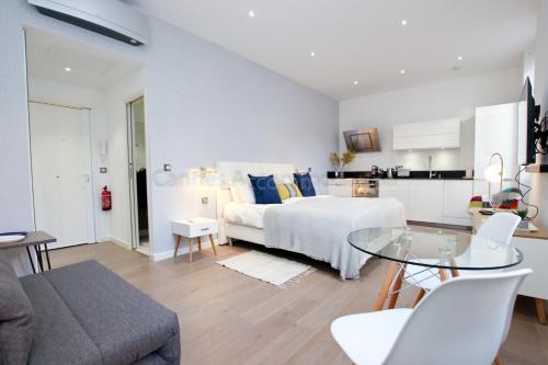 une chambre blanche avec un lit et une table en verre dans l'établissement Pampelonne, à Cannes