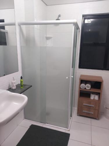 a white bathroom with a shower and a sink at Flat próximo ao Shopping e Praia in São Vicente