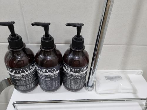 a group of three bottles on a shelf in a bathroom at Yeosu UTOP UBLESS All Rooms Stunning Ocean View in Yeosu