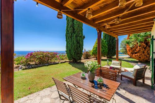 a wooden table and chairs under a wooden pergola at Villas la Gomera in Alajeró