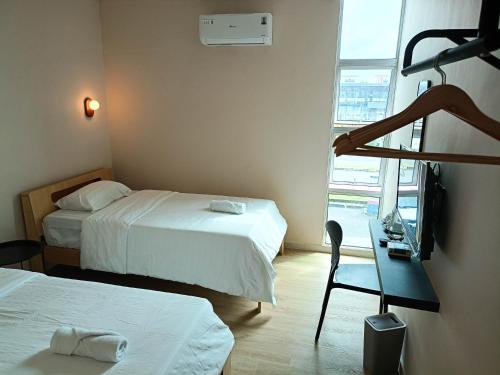 a hotel room with two beds and a desk and a window at Keteri Boutique Hotel in Kangar