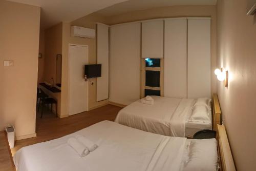 a hotel room with two beds and a desk at Keteri Boutique Hotel in Kangar