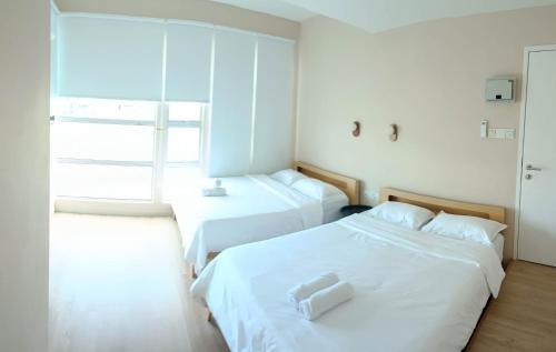 two beds in a small room with a window at Keteri Boutique Hotel in Kangar