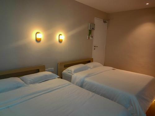 a room with two beds and two lights on the wall at Keteri Boutique Hotel in Kangar