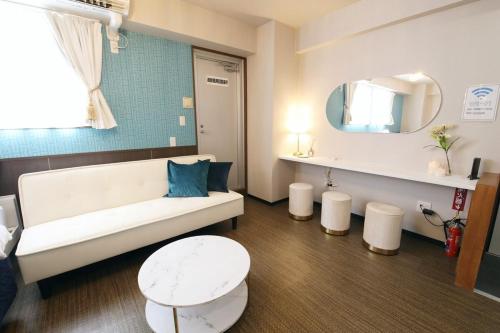 a living room with a white couch and a mirror at Tommy Condominium Wakasa 201 in Naha
