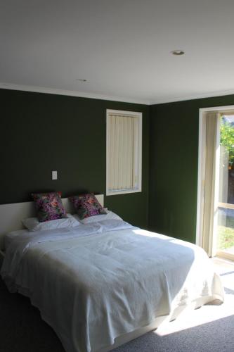 a green bedroom with a large bed with white sheets at Hamilton East Haven in Hamilton